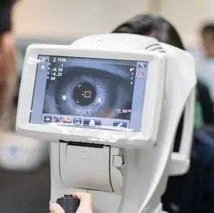 An eye testing machine is used in a medical setting with a person holding it, possibly for an eye test.