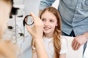 A young girl is having her eyes examined by a doctor at an eye clinic