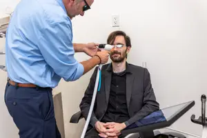 A man is having his eyes examined by a doctor using a medical device