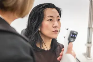 A woman is having her eye examined by a doctor using a medical device.