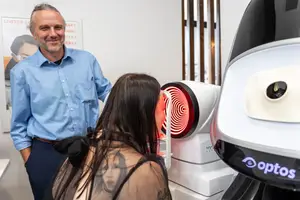 A man and woman are standing in front of an optical machine in an eye clinic.