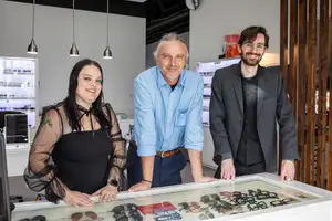 Three people standing in front of a glass case with sunglasses