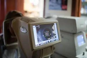A person undergoing an eye test using a machine with a monitor displaying results.