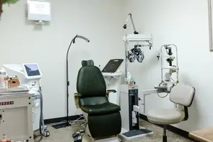 A clean medical room with an eye examination chair and other equipment