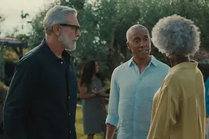 Three men and a woman stand in a garden and talk to each other