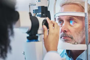 A man is getting his eyes checked by a doctor using an eye examination machine