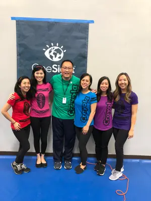 Group of women in Crayola shirts pose with a man in front of a banner
