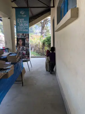 Two children peeking around a corner next to a banner that says Exit Salida