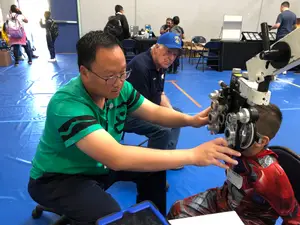 An eye doctor examines a child wearing a red costume.