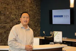 Man standing in front of a desk in an optometrist's office