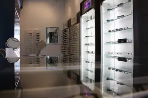 A room with glass display cases and mirrors, showcasing sunglasses and eyeglasses on shelves.