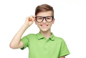 A smiling boy with brown hair wearing glasses and a green polo shirt.