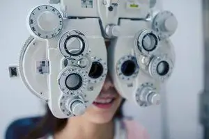 A woman is having her eyes examined by an optometrist using an eye examination machine.