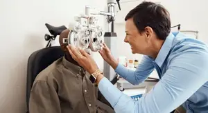 An adult male is getting his eyes examined by an adult male doctor in an eye clinic.