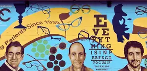 A vibrant mural depicting three male figures and various optical elements, including glasses and a wine glass, set against a colorful backdrop with text reading 'EVE RY THING IS IN PERFECT FOCUSIF YOURVISIO NISALRIGHT', and a historical timeline on the wall from 1900 to 1970.