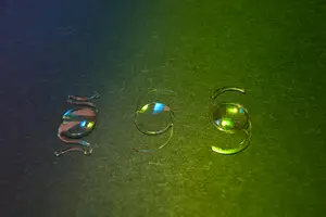 Three glasses lenses with different colors on a green surface