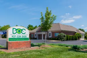 Dayton Optometric Center sign in front of a brick building with a tree and green lawn