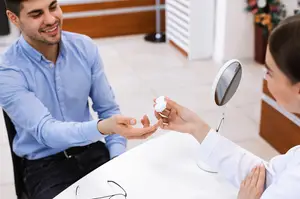 optician giving container with contact lenses to male patient
