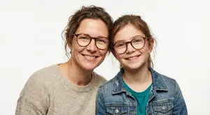 An adult woman and a young girl are smiling for a portrait