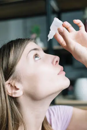 Closeup of a woman with her eyes closed while applying eye drops