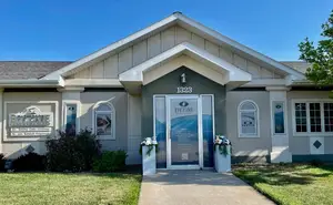 Front view of the Eye Care building with a sign that reads Eye Care, two vases with flowers, and a pathway leading to the entrance.