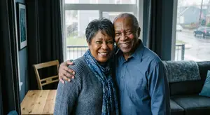 An elderly man and woman smiling together in their home living room