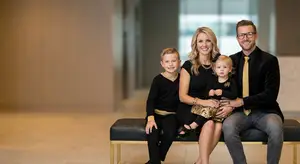 Family photo with father, mother, son, and daughter sitting on a bench
