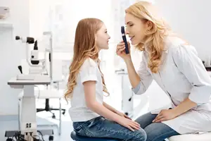 A woman doctor is checking the eyes of a girl in a clinic.