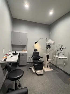 An empty eye clinic with a desk, chairs, and medical equipment.