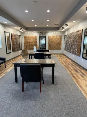 An interior of a room with a wooden desk, a black chair, and mirrors attached to the wall.