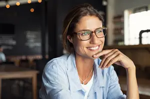 An adult woman sitting at a table in a cafe smiling at the camera