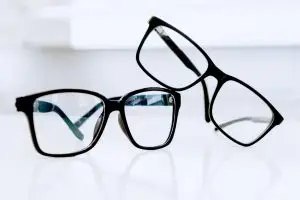 A pair of black rectangular glasses with clear lenses on a white surface