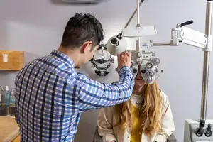 Man adjusting a woman's eye exam glasses in an optometrist's office