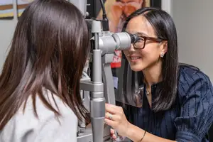 Optometrist examining a patient's eyes with an ophthalmoscope