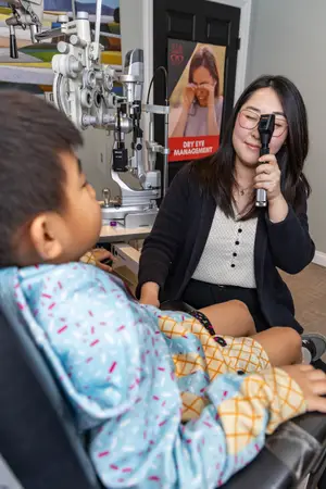 An eye doctor examining a child's eyes using an ophthalmoscope.