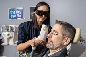 woman with dark glasses using laser treatment on a man's eye