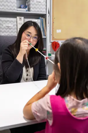 A woman is playing with a child using a string of beads