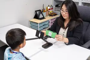 A woman is teaching a boy with the help of a magnifying glass and a book