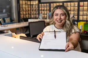 A woman holds a clipboard and smiles in an office with a bright and organized interior design