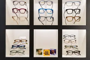 A display case containing multiple pairs of glasses with different frames and lenses, placed on a white background.