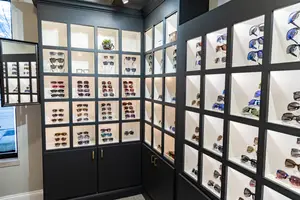 A glass display cabinet with several different colored sunglasses inside it