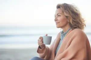 Woman sitting on the beach with a coffee cup