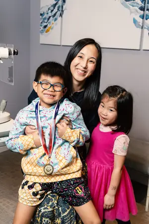 A woman and two kids are posing for a photo inside a room, maybe in a studio