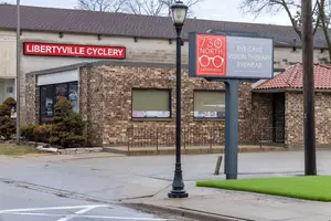 A building with a brick wall and glass windows that has a sign that reads Libertyville Cyclery and 730 North Eye Care Vision Therapy Eyewear Optometry on the sidewalk in front of it.