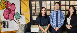 Three people stand in front of a display of glasses in a store