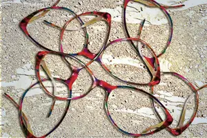Several colorful eyeglasses frames are placed on a textured surface.