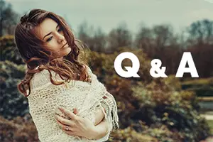 A woman with brown curly hair and eyes closed stands in a natural setting with a white shawl, looking to the left, and the words 'Q & A' are written in white on a blurry background.