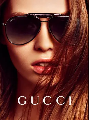 Close-up of a woman wearing Gucci sunglasses with long brown hair.