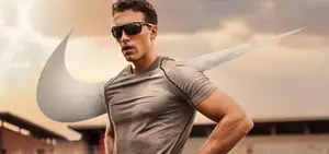 Man wearing sunglasses and a gray t-shirt running in an outdoor setting with a Nike swoosh graphic on the side