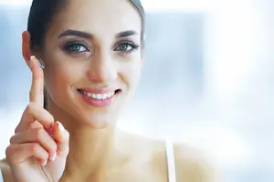 A woman is smiling and wearing a ring in her ear.